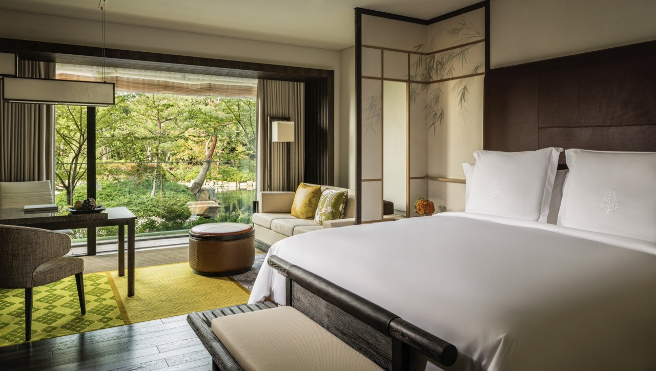 Guest rooms feature floor-to-ceiling windows and shoji-inspired screens that frame views of the pond and surrounding gardens