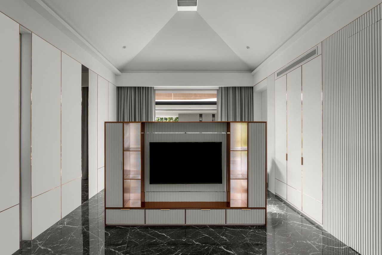 One of the rooms features a custom entertainment unit with fluted panels and black marble flooring