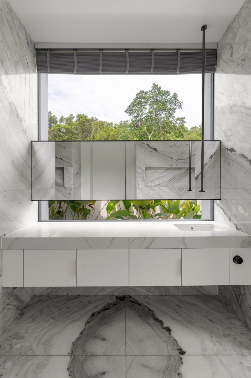 The bathroom design frames views of the secondary forest behind the property