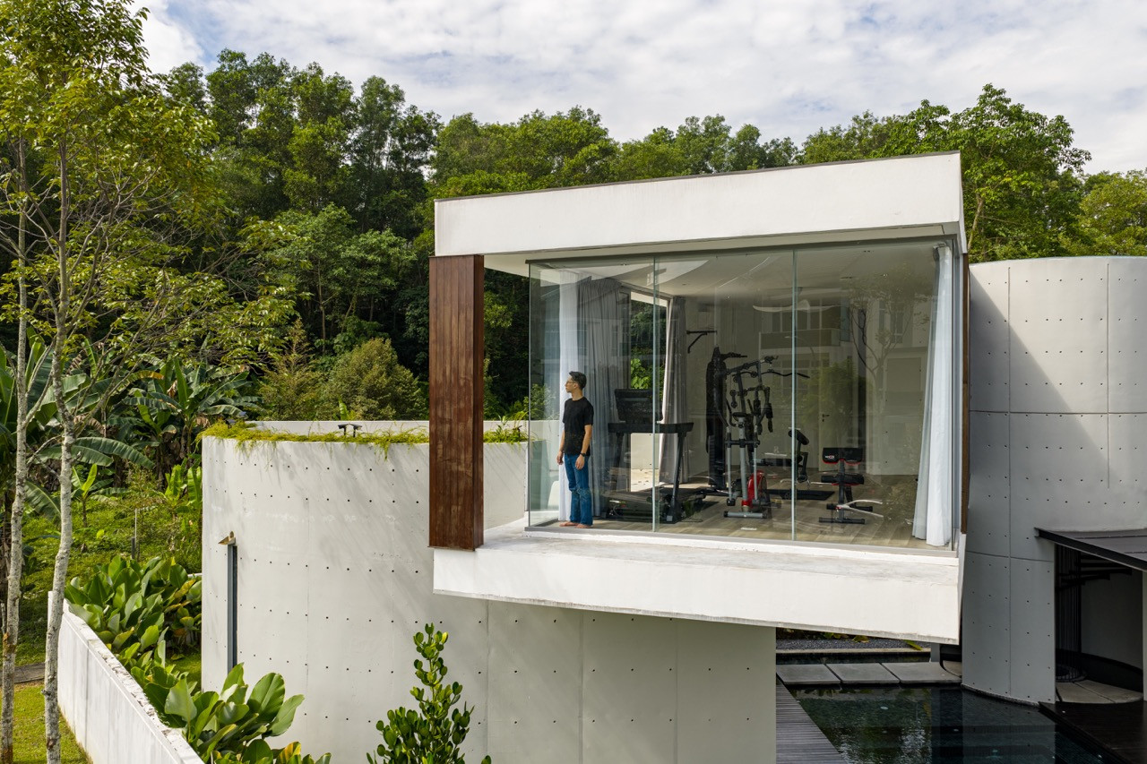 The elevated gym pavilion with floor-to-ceiling glass opens to forest views