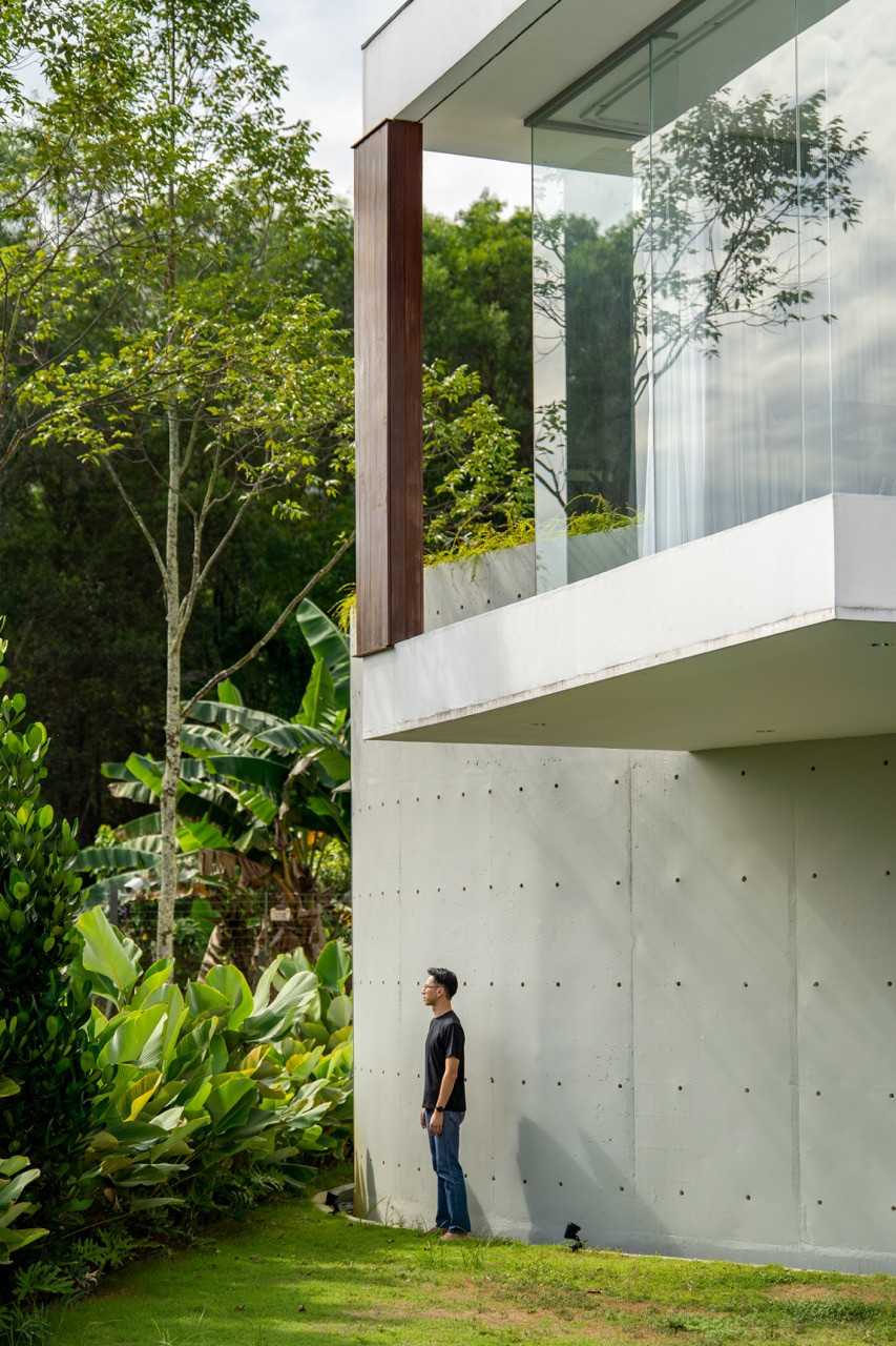 The cantilevered upper level with timber cladding sits above the cylindrical concrete staircase
