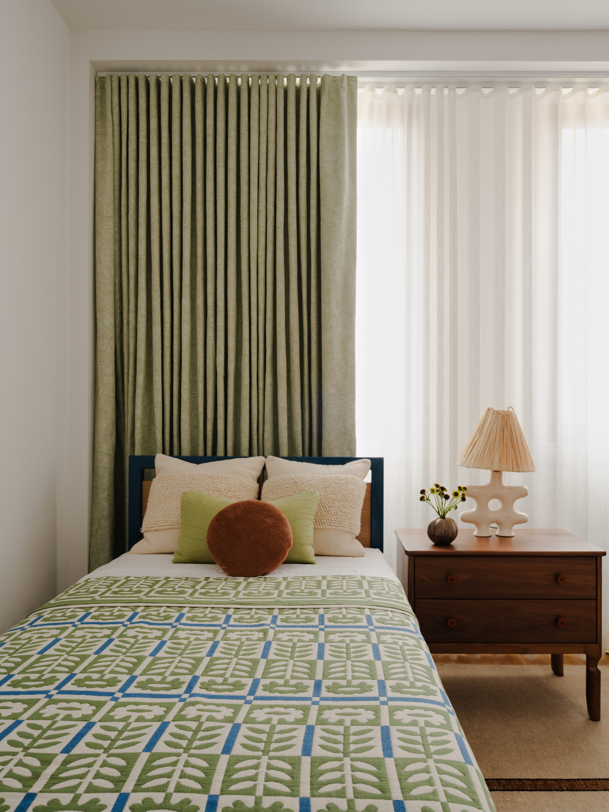 The bedroom of a Brooklyn townhouse designed by Lucy Harris, which pairs playful vintage textures with commanding wooden pieces and ceramic accents