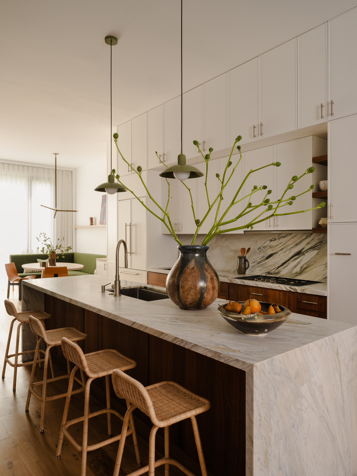 The kitchen of a Brooklyn townhouse designed by Lucy Harris, contrasting a marble countertop with rattan chairs