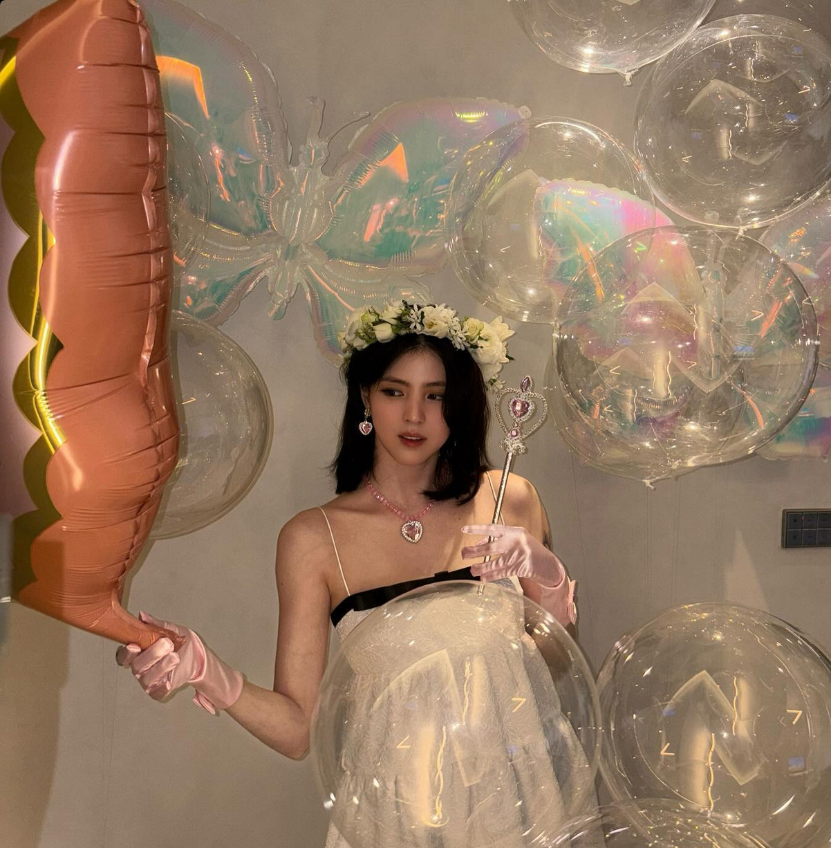 A white babydoll dress transforms with floral crown, pink gloves and toy jewellery (Photo: @xeesoxee / Instagram)