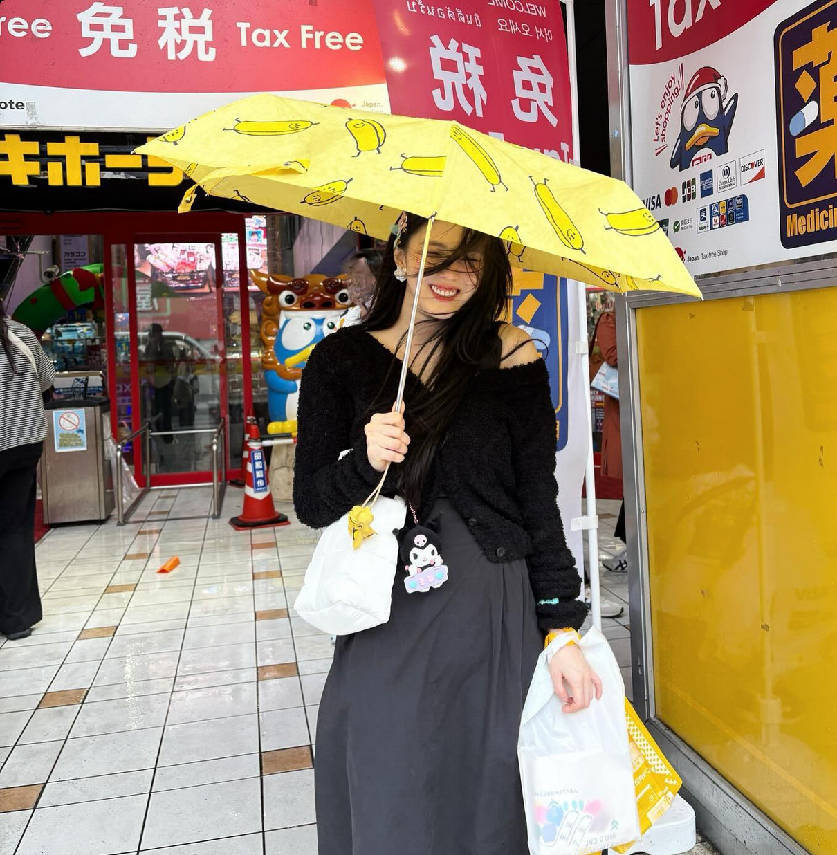 Black cardigan elegance meets banana umbrella whimsy and personalised bag charms (Photo: @xeesoxee / Instagram)