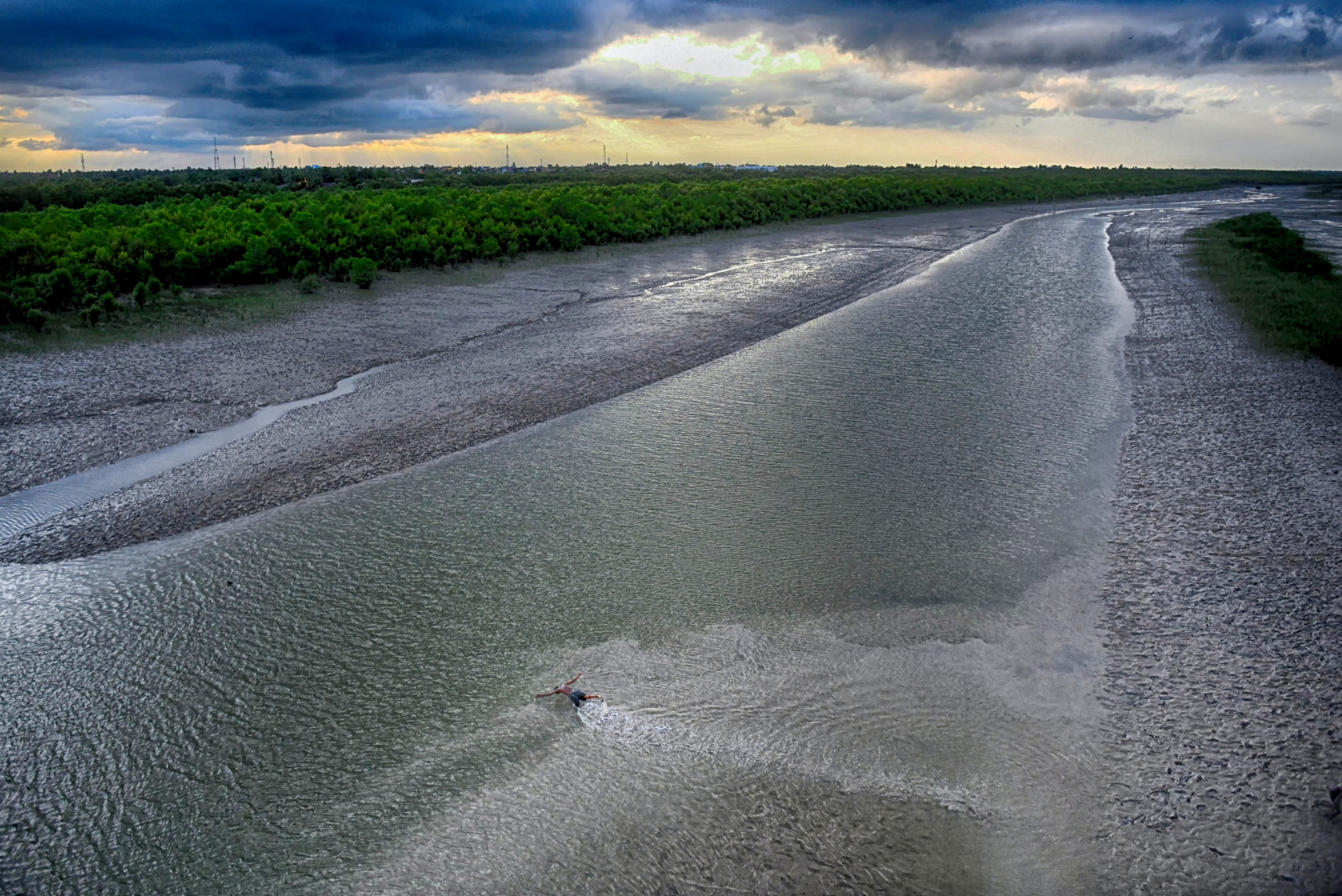CANNING, WEST BENGAL, INDIA - 2025/06/15: A child takes a bath after fishing on the Matla River. In the Indian Sundarbans, particularly along the western banks of the Matla River, rising sea levels and rapid coastal erosion are forcing fishermen and wildlife into shrinking territory. The sea level has increased by 35 centimeters annually over the past two decades, making it one of the fastest-eroding coastal regions globally. As land disappears, both humans and endangered Bengal tigers are being pushed into