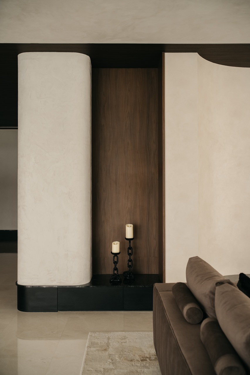 A cylindrical column in the living area includes a recessed timber niche with candle holders