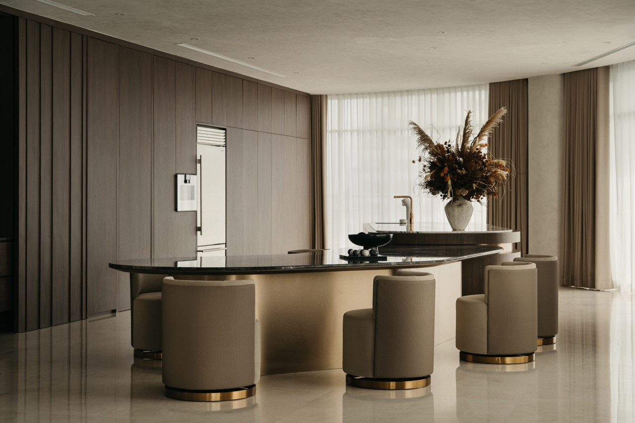 The open-plan space shows the relationship among the kitchen cabinetry, the curved counter, and the living