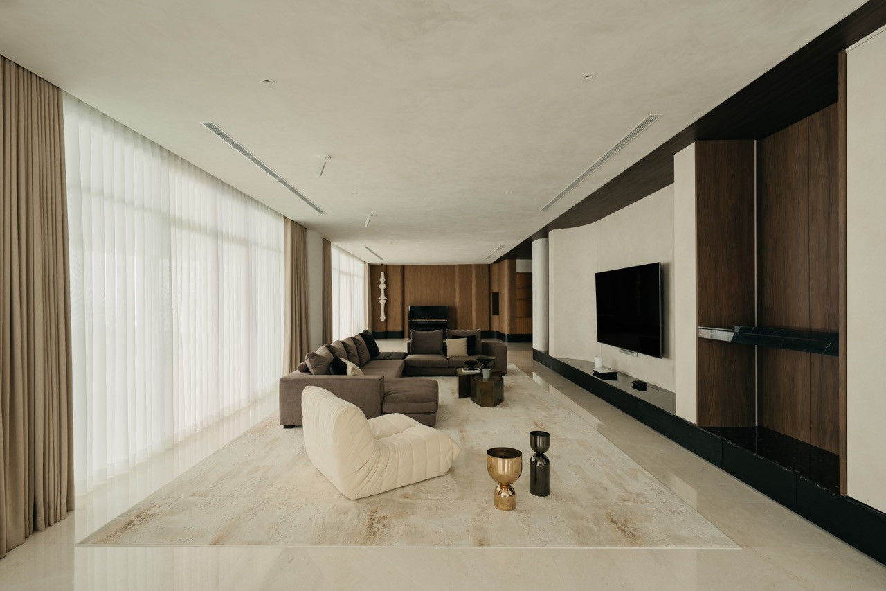 The full length of the living area shows floor-to-ceiling windows, the media wall and seating arrangement