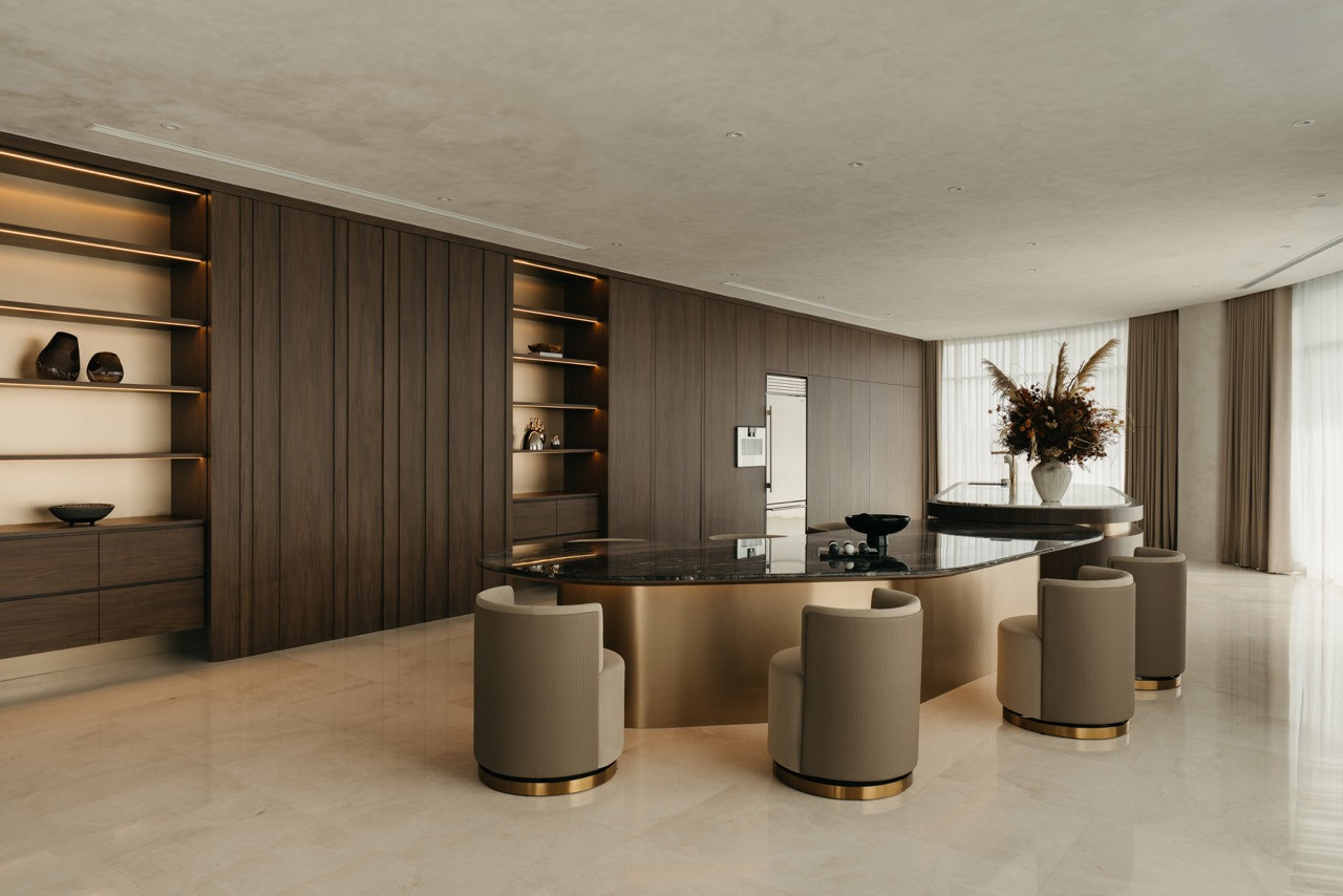 The curved island counter sits in the centre of the open plan, with integrated timber cabinetry forming the kitchen backdrop