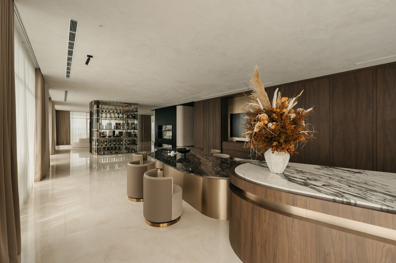 The full open-plan space shows the curved island counter, spirits cabinet and living areas while the texture-painted ceiling creates depth