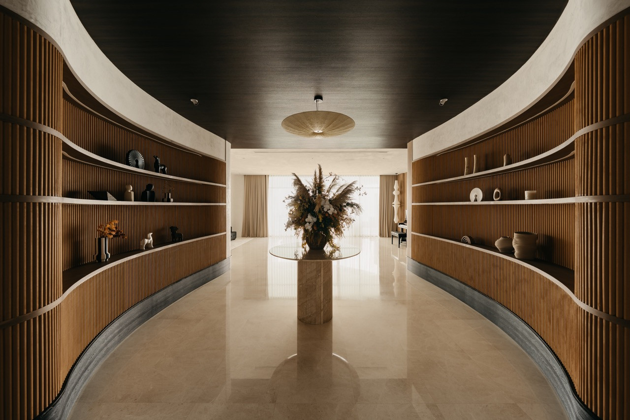 The curved display corridor runs between two walls of backlit timber shelving
