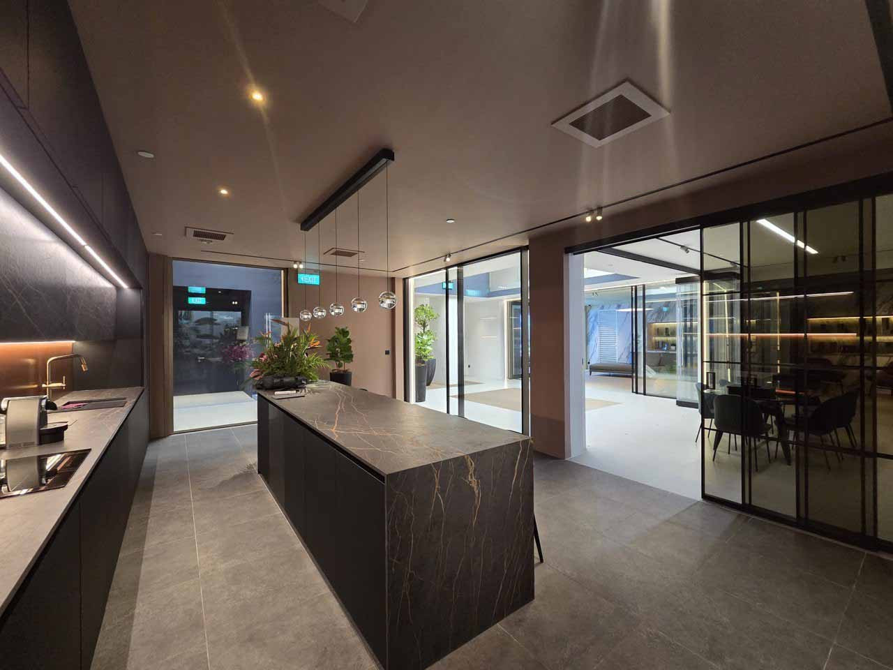 The moody kitchen area is subdued and elegant, with sliding doors separating it from the rest of the showroom