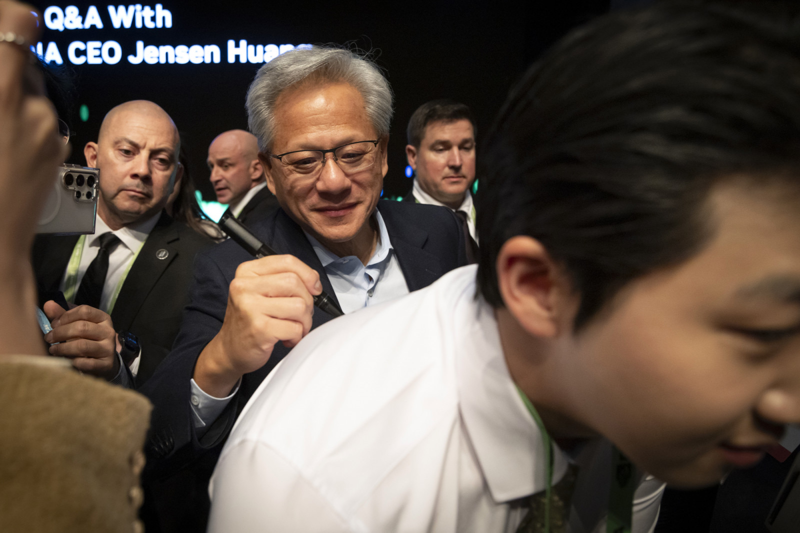 GYEONGJU, SOUTH KOREA - OCTOBER 31: Jensen Huang, NVIDIA founder and CEO, gives his autograph to a reporter at a press conference during the APEC CEO summit on October 31, 2025 in Gyeongju, South Korea. Leaders and delegates from 21 APEC economies are gathering in South Korea for the upcoming APEC summit, where talks are expected to center on trade, supply chain stability, and technology cooperation. The meetings come amid heightened regional tensions and efforts to boost growth through closer economic int