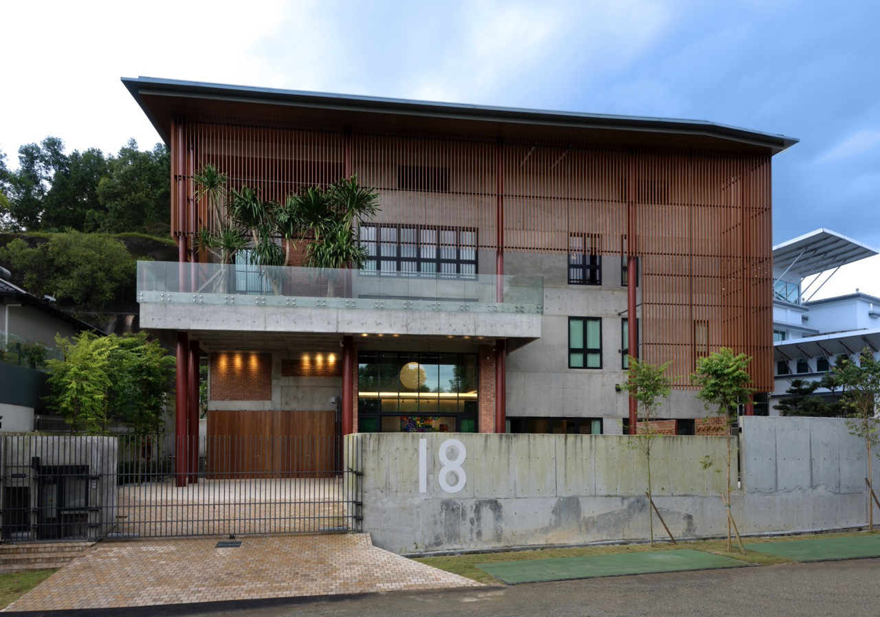 The street elevation shows the timber louvred facade above the concrete base, with planting on the upper terrace softening the hard surfaces