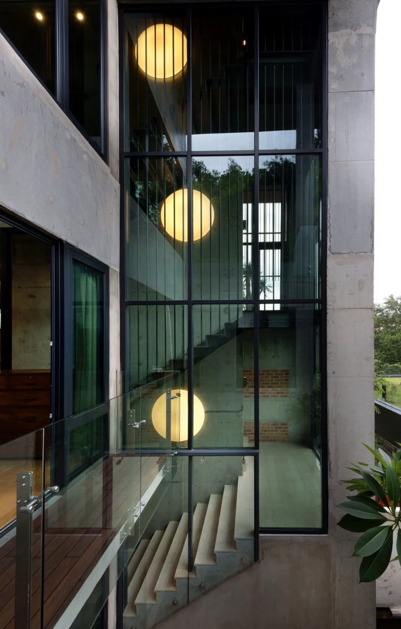The glass-enclosed stairwell runs through all three levels, with circular pendant lights marking each floor with steel and glass balustrades allowing light to penetrate the circulation core