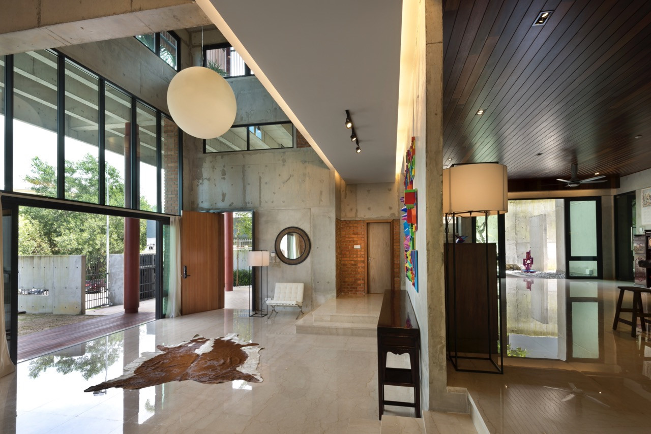 The double-volume entrance hall shows the relationship between the marble floor level and mezzanine above, with full-height glazing connecting interior spaces to external courtyards.
