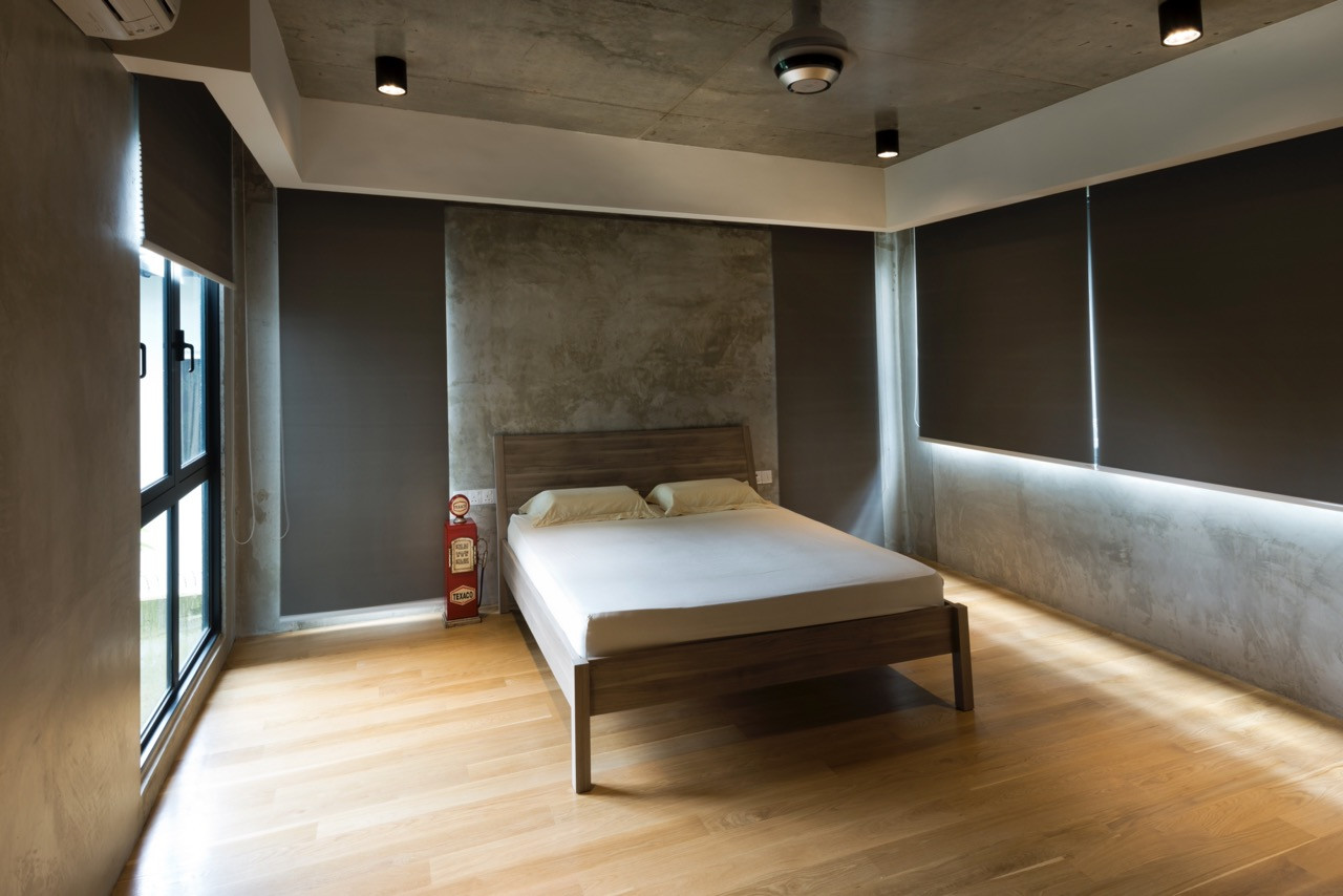 Timber flooring and a simple platform bed sit against concrete walls, with concealed lighting along the base and a minimalist material palette throughout