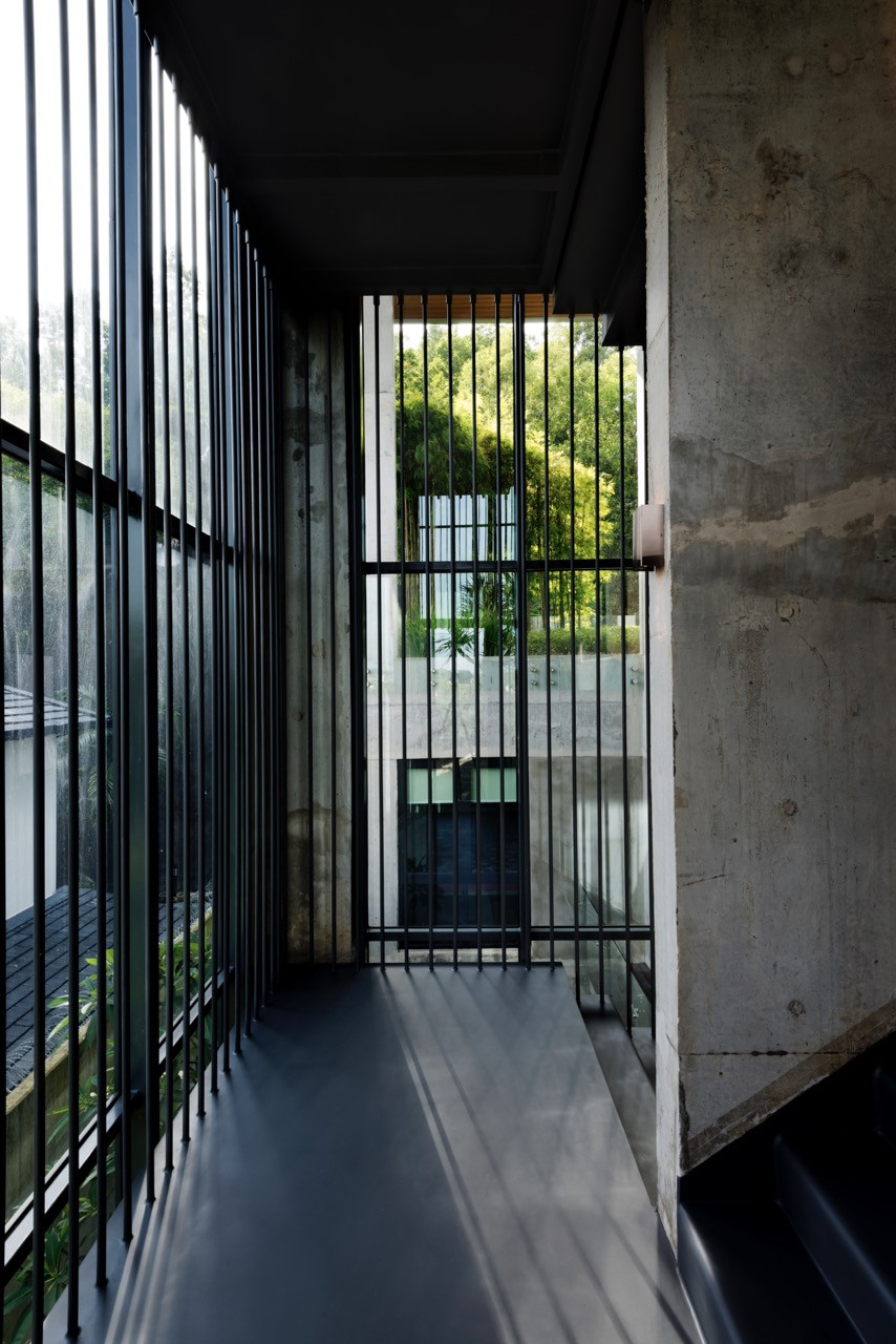 Vertical metal screening elements run along the stair void, filtering light and maintaining openness whilst providing safety barriers within the multi-level plan
