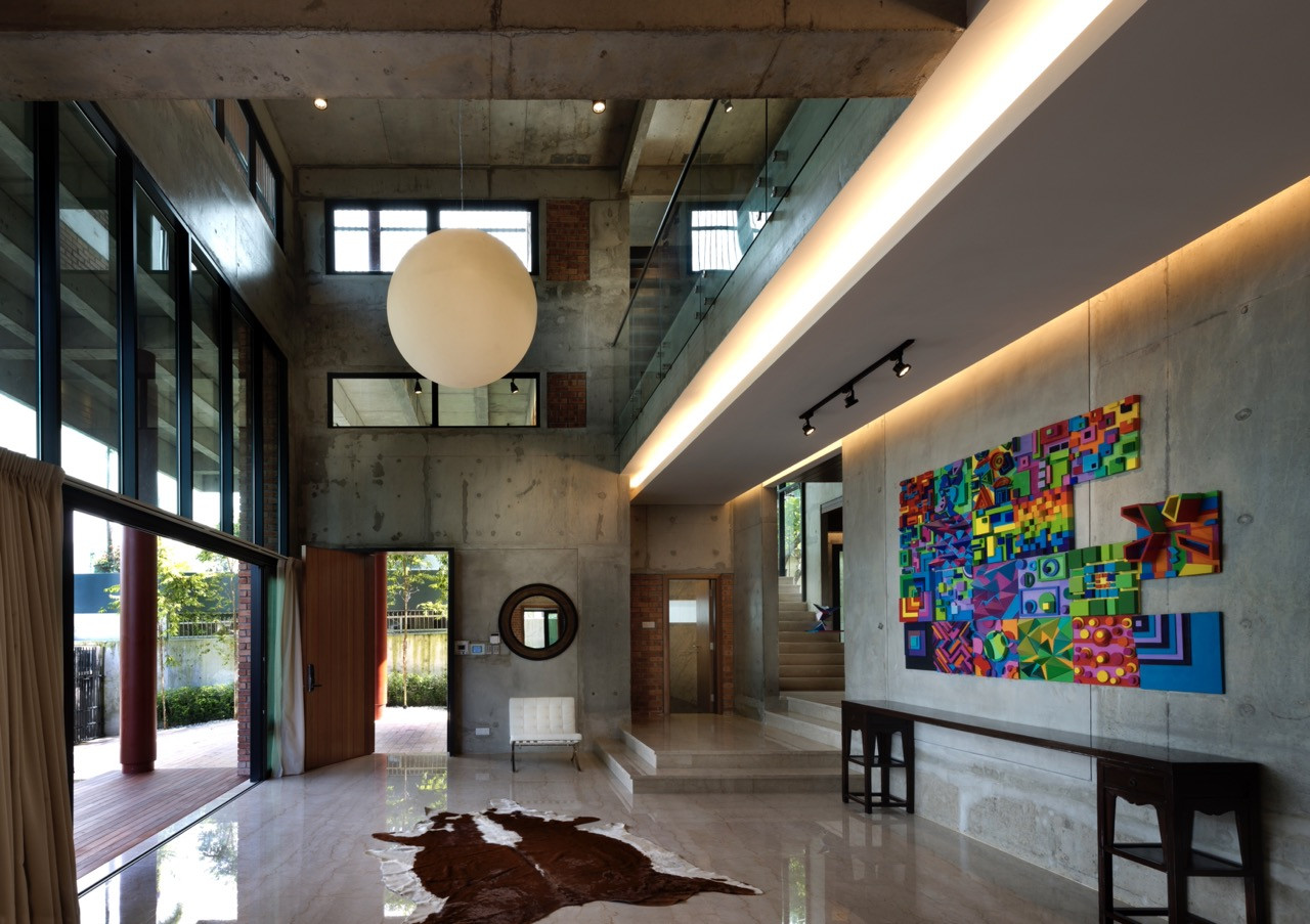 The double-volume space features exposed off-form concrete, a spherical pendant light, and contemporary artworks displayed on the concrete walls