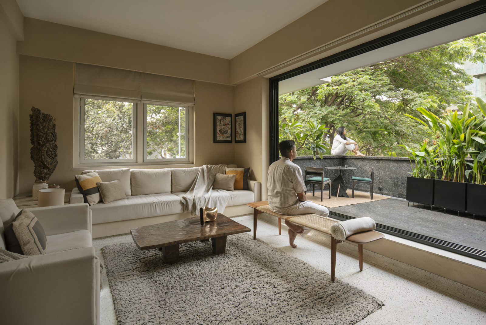 The living room and balcony of a renovated Art Deco home by Studio UF+O in Mumbai, India