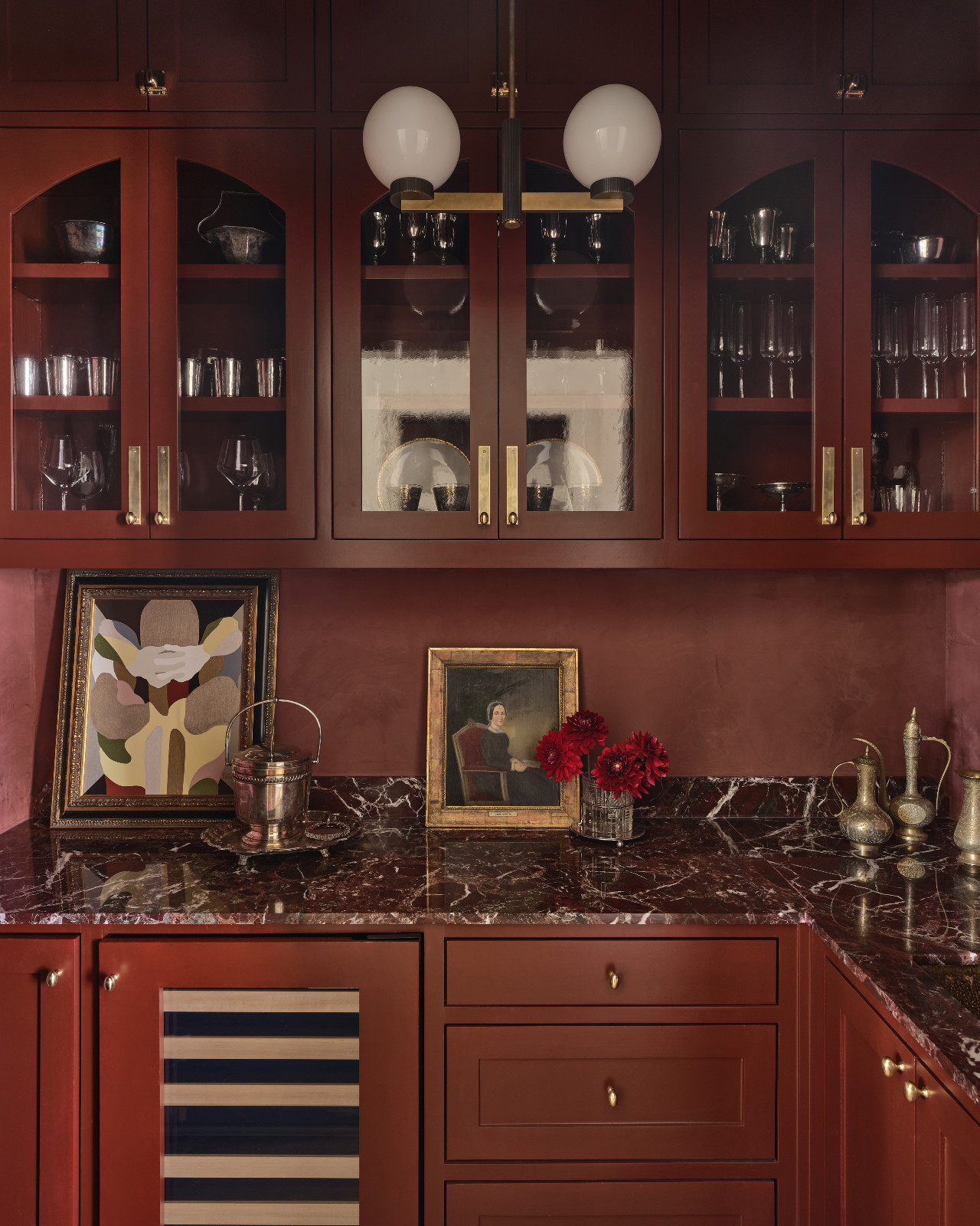 A moody, jewel-toned bar area with marble accents in a home designed by Shane & Pierce in Dallas, Texas
