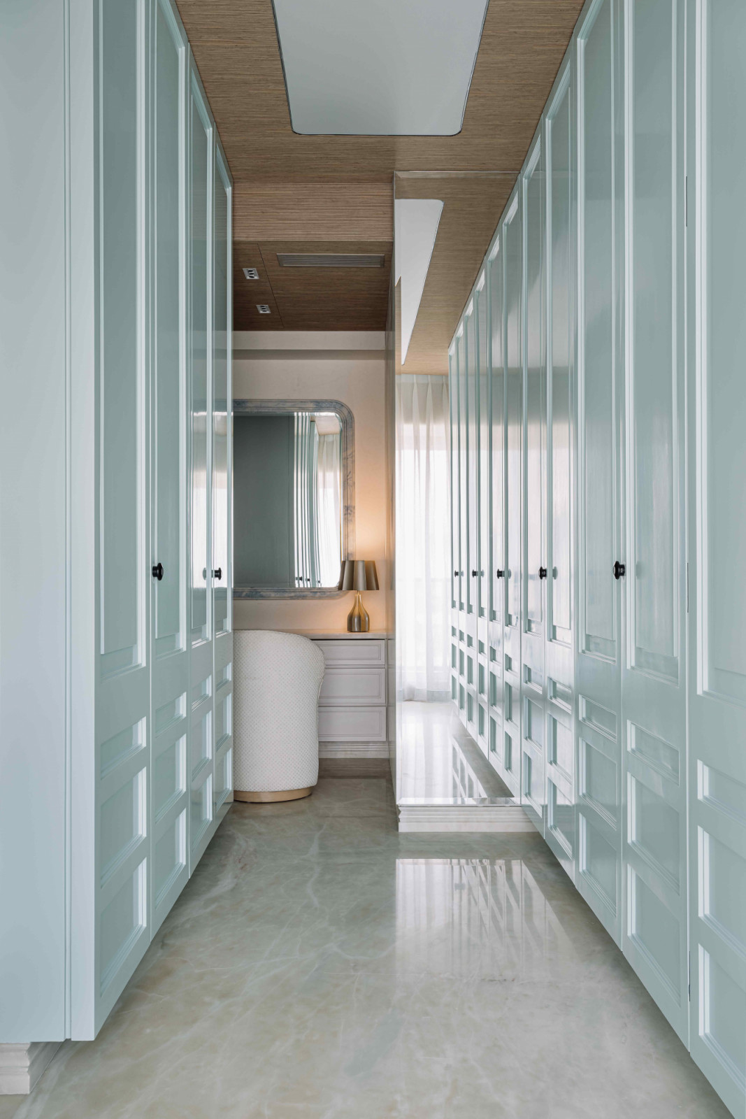 The spacious walk-in wardrobe with cabinet doors in soft pastel blue