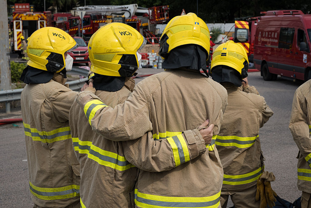 Firefighters support each other as they respond to the fires in Tai Po, Hong Kong