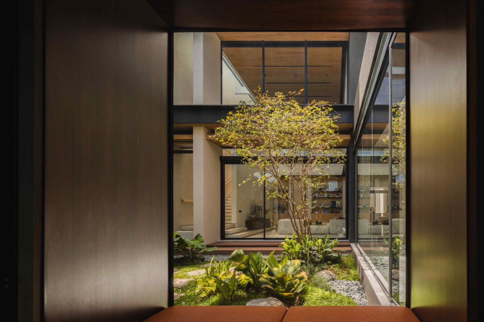 Floor-to-ceiling windows overlook the lush courtyard on one side and the private rooms on the other
