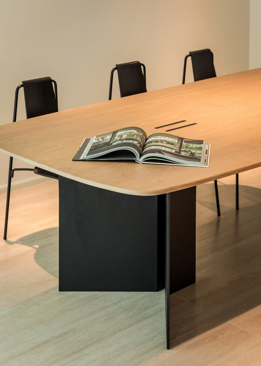 The custom dining table with black chairs demonstrates the clean lines and functional clarity that define the interior spaces