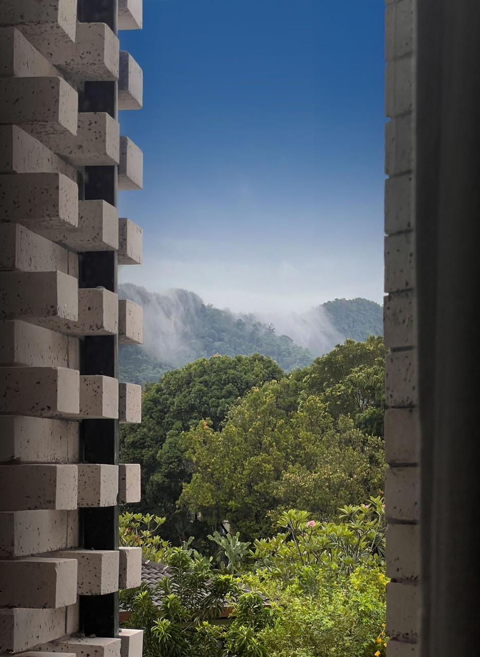 The double-skin façade clad in white, terrazzo-like custom bricks frames views of Bukit Tabur Quartz Ridge