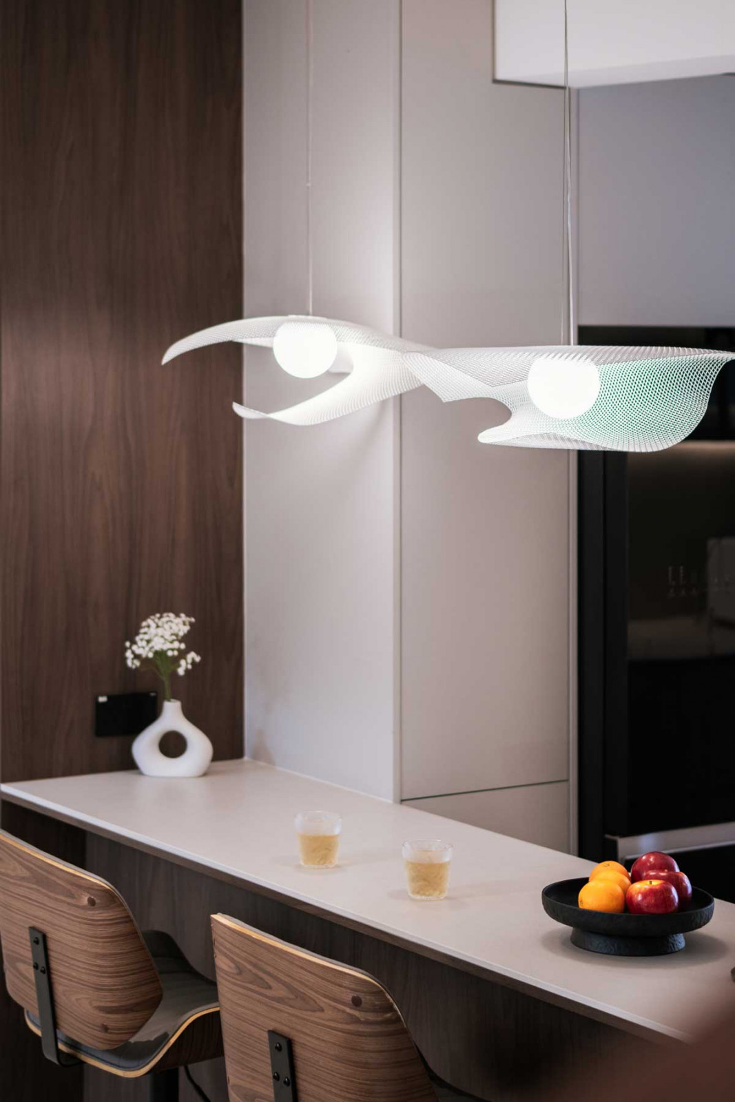 Thoughtful details, such as waterproof boards in the wet kitchen, a rounded corner to resolve a structural beam, and a dining island with concealed wireless charging, ensure practicality is seamlessly integrated into daily life