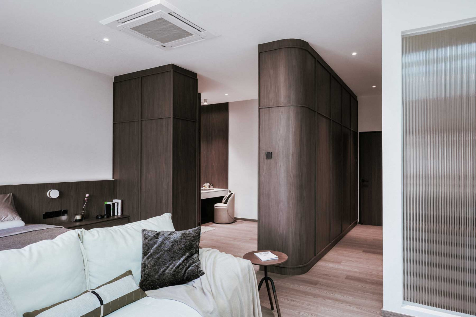 The master suite on the top floor adopts a boutique-hotel feel with a shaker-panelled entry, a lounge-like living zone, and a serene private sleeping area. Full-height reeded glass brings in soft daylight while maintaining intimacy