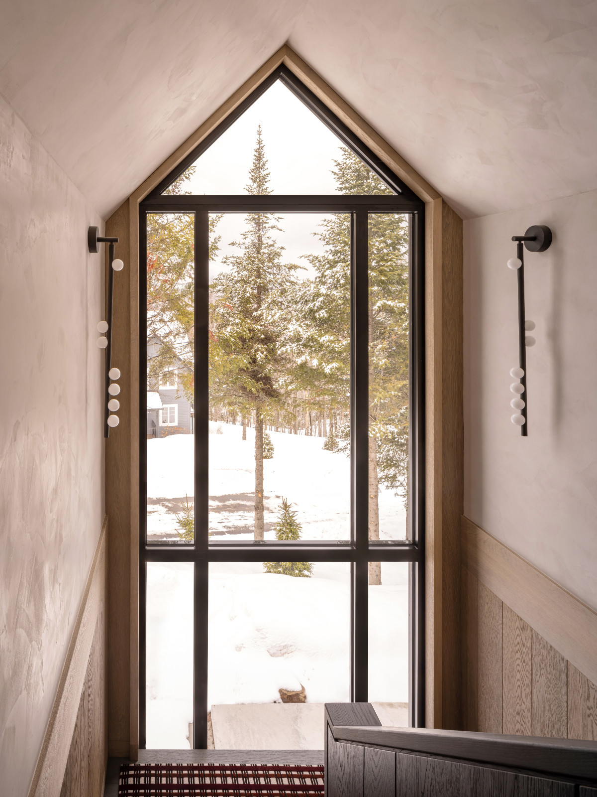 Floor-to-ceiling windows reveal a breathtaking winter view at a renovated ski chalet in Quebec, Canada, designed by ACDO
