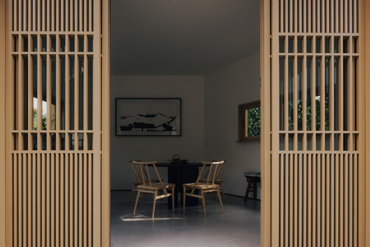 A well-curated interior peeks through sliding doors articulated with timber detailing inspired by birdcages