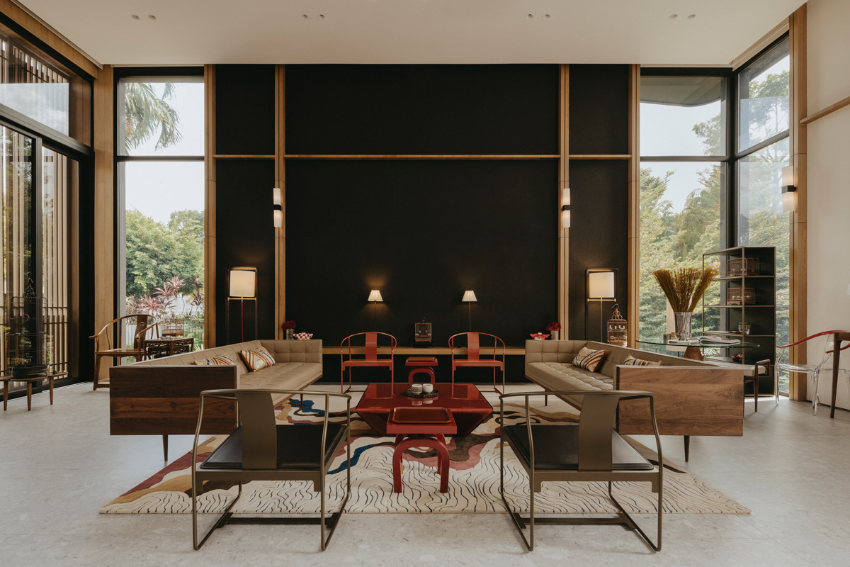 The red-finished furniture pieces at the centre of the living room create a striking contrast against the black wall in this Good Class Bungalow