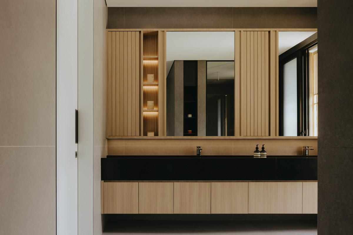 The master bathroom, featuring his-and-hers sinks, continues the same material palette