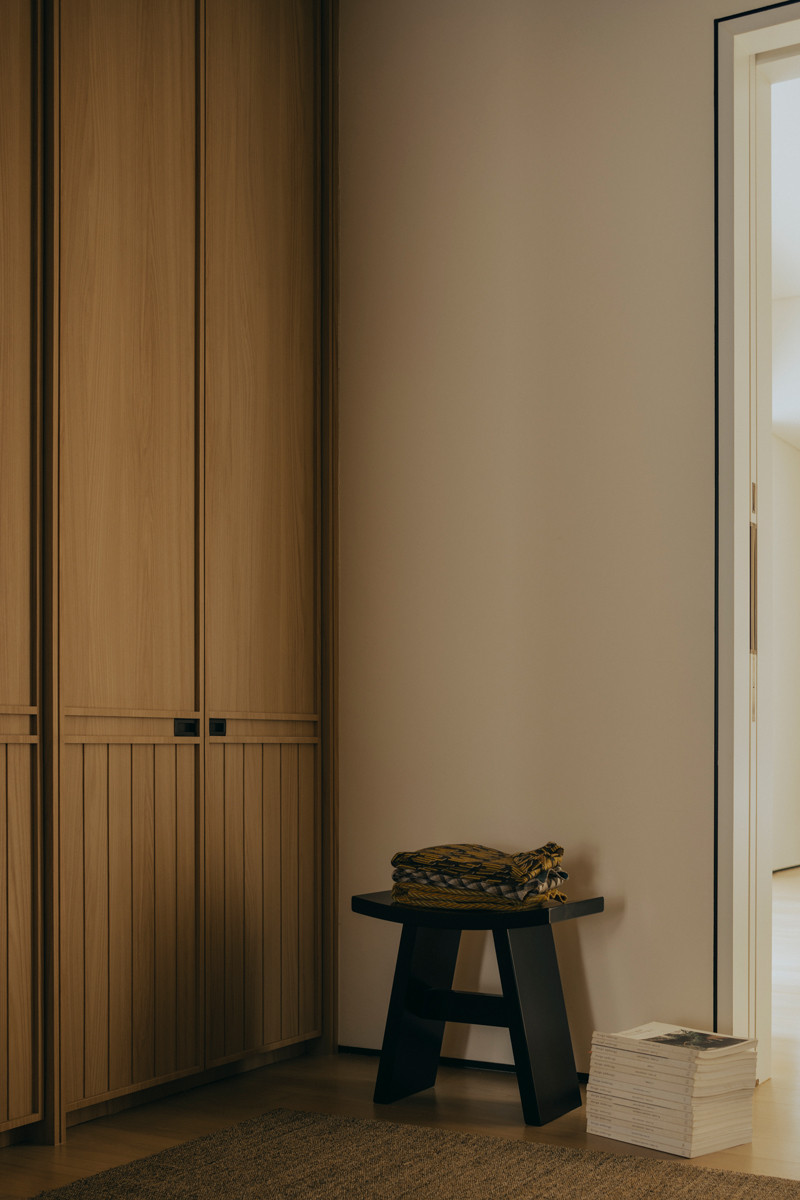 A dark-finish stool offers a striking contrast to the pale wood joinery in this corner