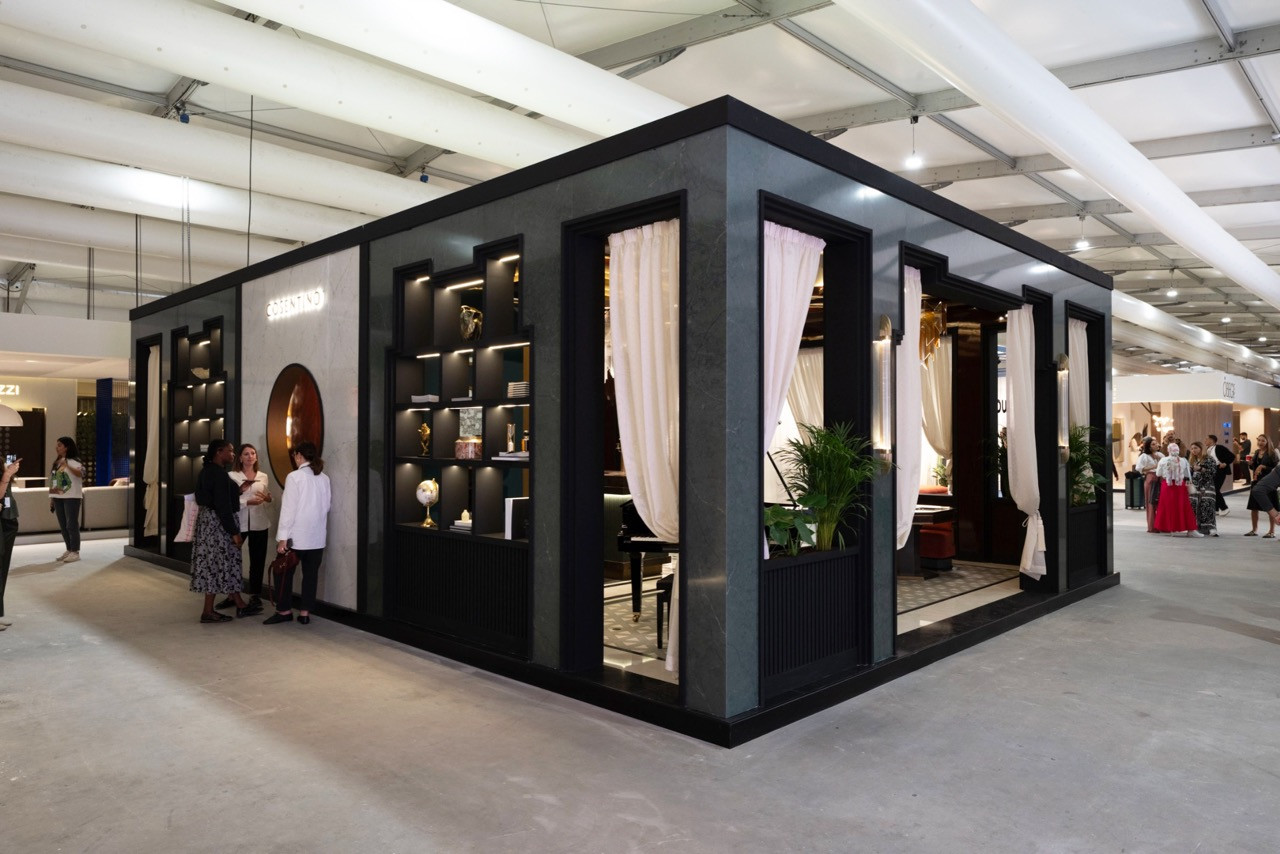 The exterior of Cosentino’s booth on the Downtown Design fair floor shows the self-contained pavilion structure clad in dark surfaces with large openings that reveal the Art Deco-inspired interior and allow visitors to glimpse the lounge atmosphere from outside