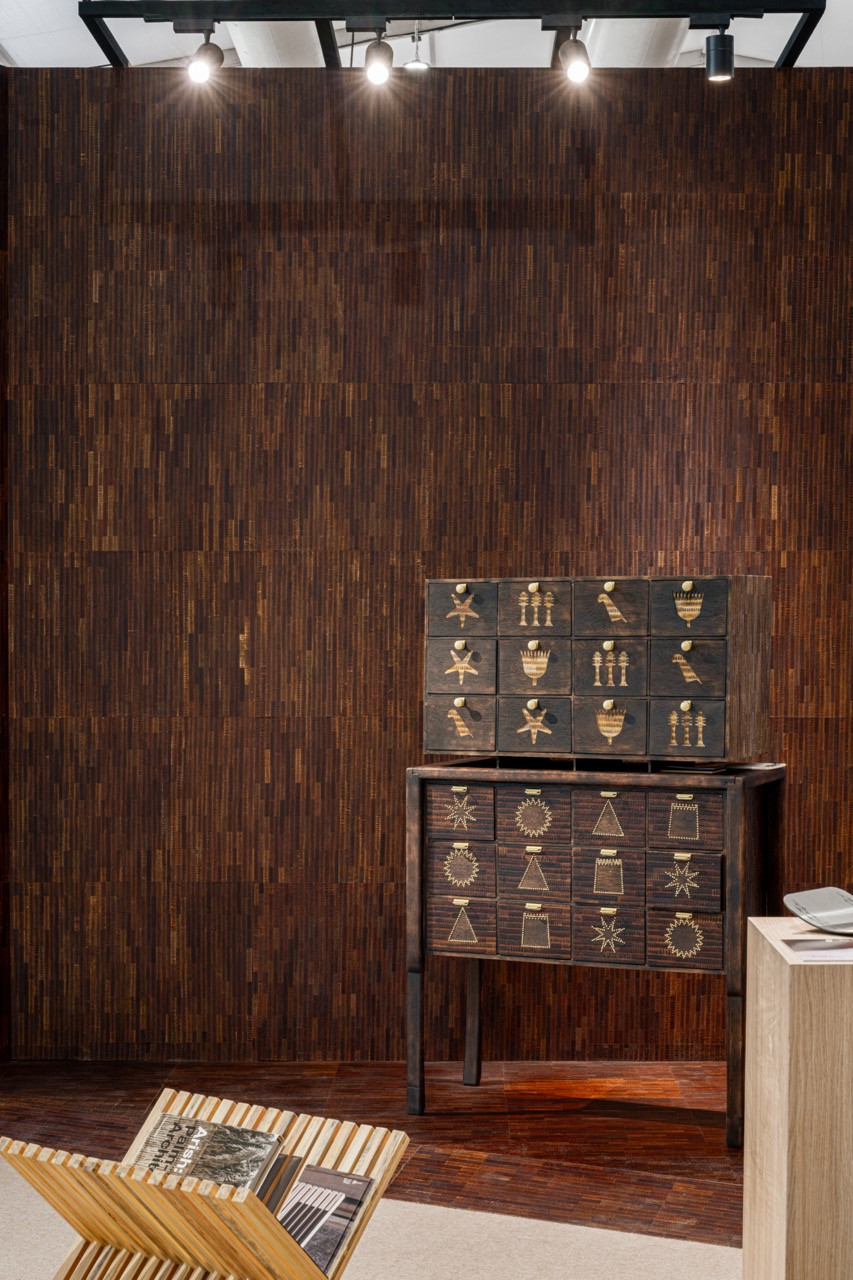 Nuhayr Zein's 'Sara'ir' cabinet in Leukeather (made from seed pods) features drawers etched with Egyptian and Emirati motifs, displayed against PlyPalm palm frond cladding at the 1971 Design Space booth