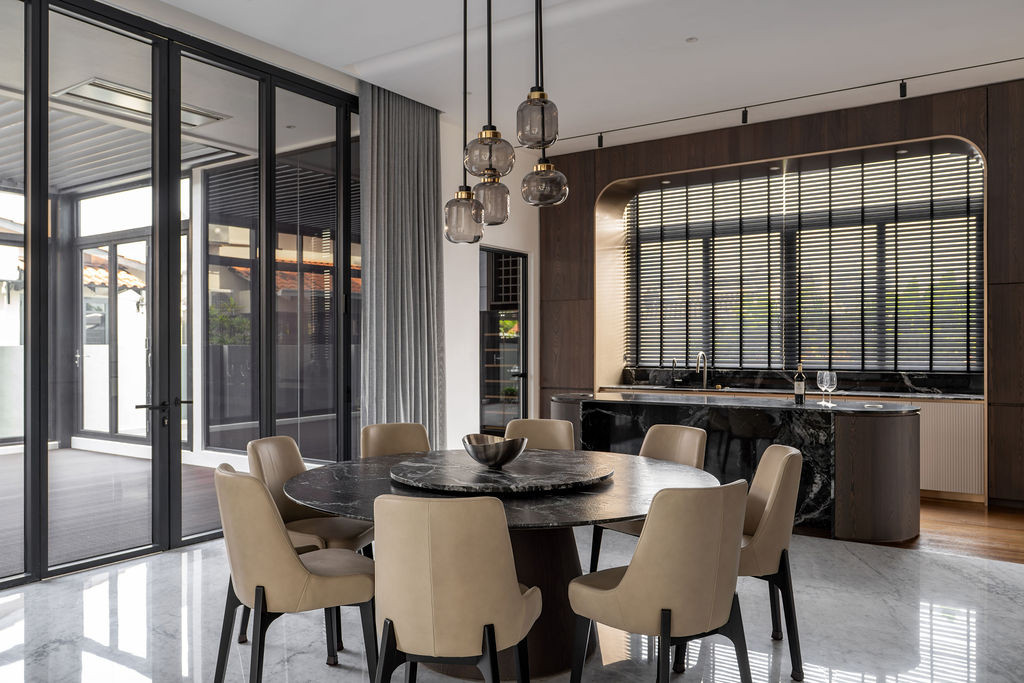 The dining area features clustered pendant lights above a marble-topped table, with the wet bar's green-veined marble visible in the background through the arched opening