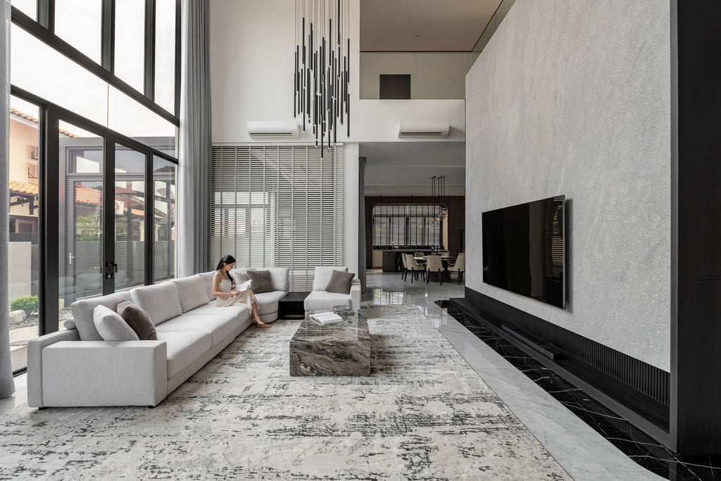 The living space showcases the flamed granite feature wall rising the full height of the double-volume ceiling, whilst the suspended linear chandelier accentuates the void and frames sight lines