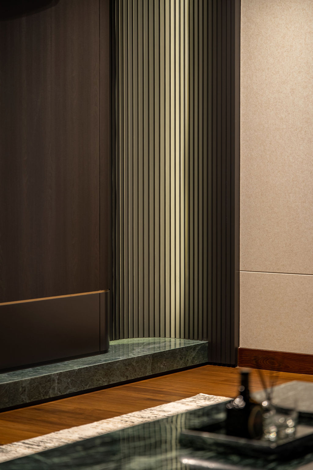 The entertainment room features a green-veined marble island with vertical fluted detailing against dark wood cabinetry with bronze trims