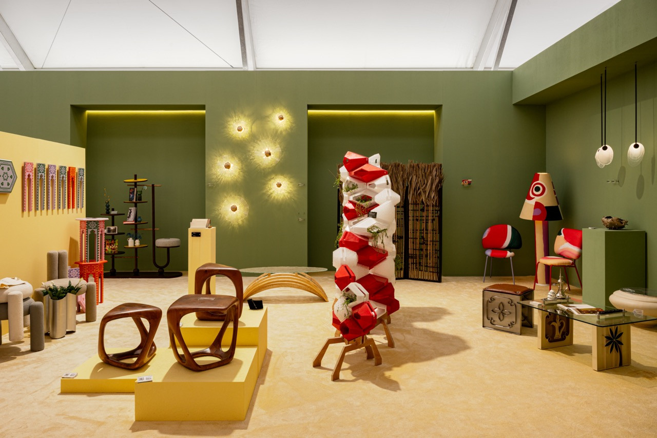 The exhibition space combined furniture, lighting and textiles including palm frond room dividers, wall-mounted sconces, and sculptural wooden seating pieces