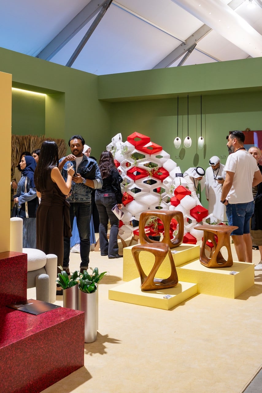 The exhibition space combined furniture, lighting and textiles, including palm frond room dividers, wall-mounted sconces, and sculptural wooden seating pieces