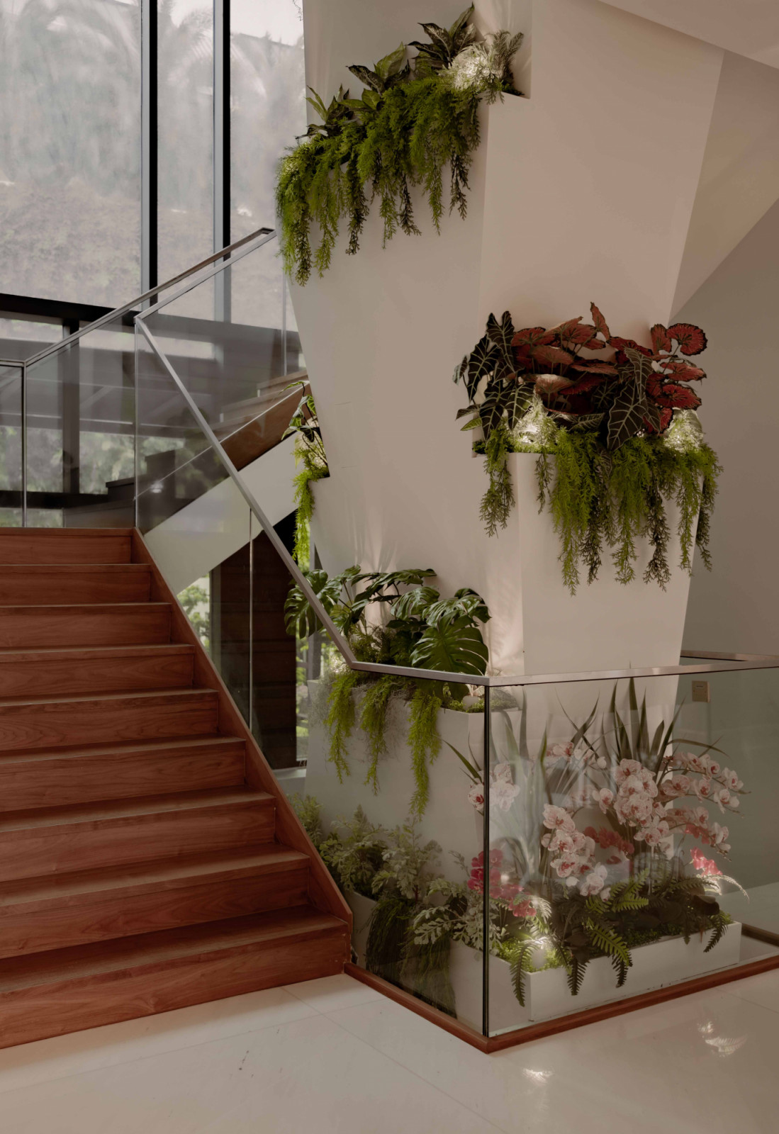Planters dotting a structural column on the stairwell, layering greenery vertically to soften circulation spaces and reinforce the multigenerational home’s biophilic thread