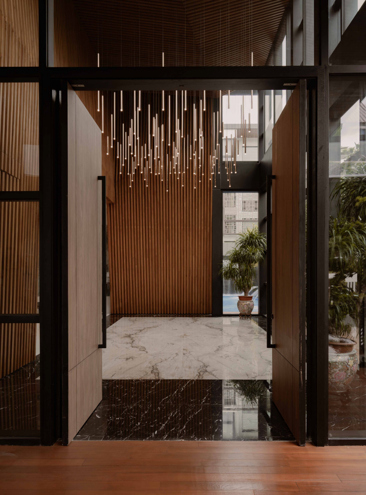 At the multigenerational home’s main entrance, a double-volume threshold is animated by a cascading light installation