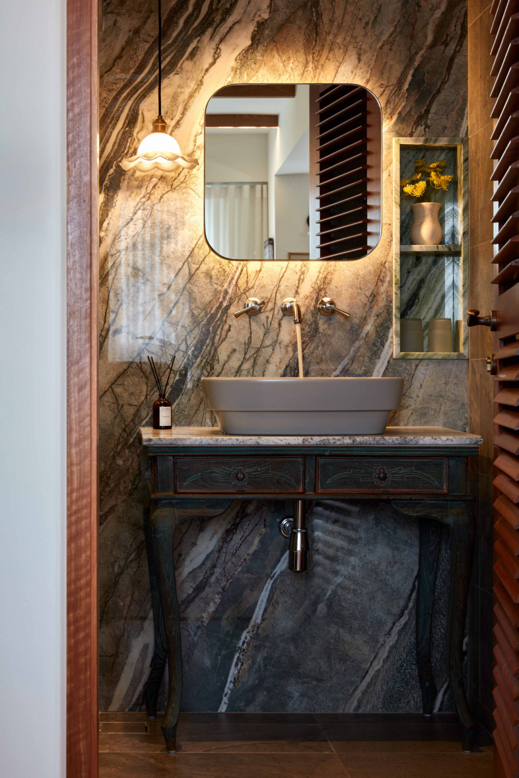 An antique console is utilised as a unique vanity in the powder room, which also uses Peacock sintered stone as a feature wall