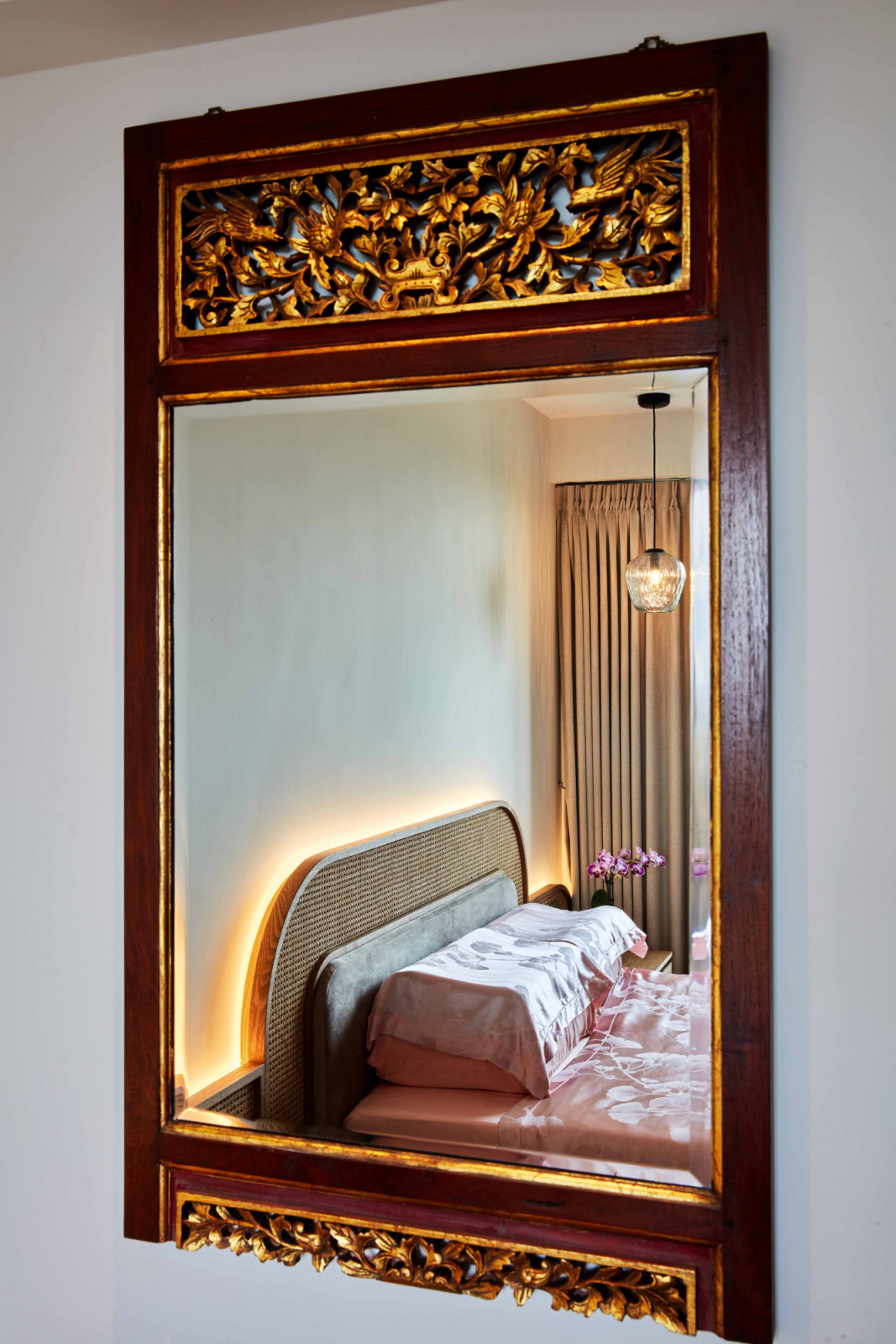 An elaborately carved antique mirror elevates this bedroom with its rich wood tone