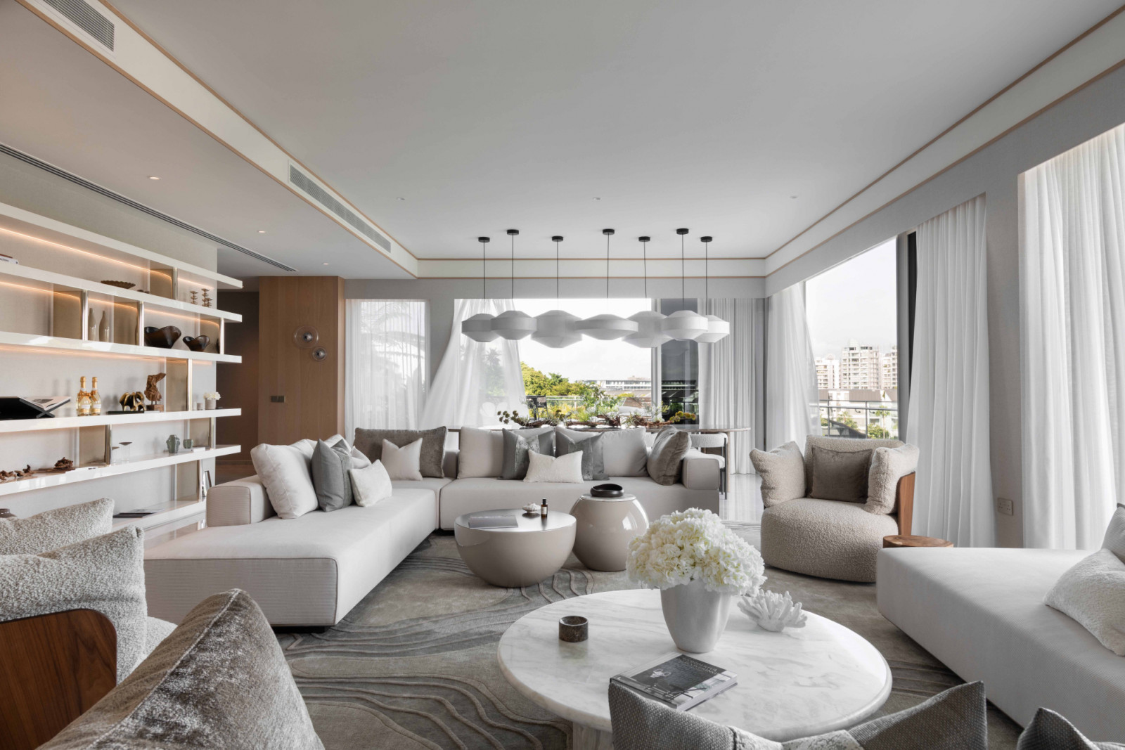 Perfectly suited to social interaction and entertaining, the spacious living area of this Ho Bee Land super penthouse features a wealth of seating options and an abundance of natural light that adds nuanced depth to the largely neutral palette